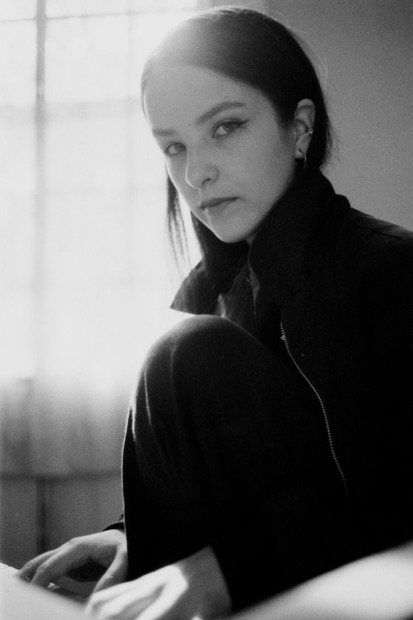 Woman sitting and watching direct into the camera.